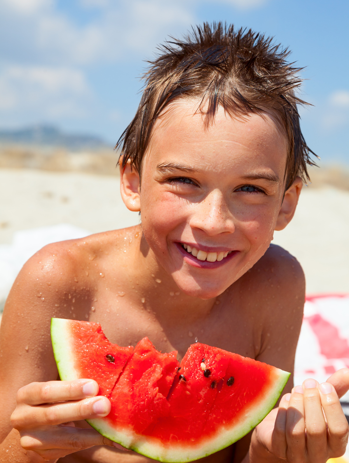 Boy eating melon on a beach